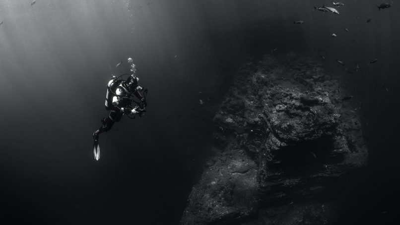 grayscale photo of person scuba diving