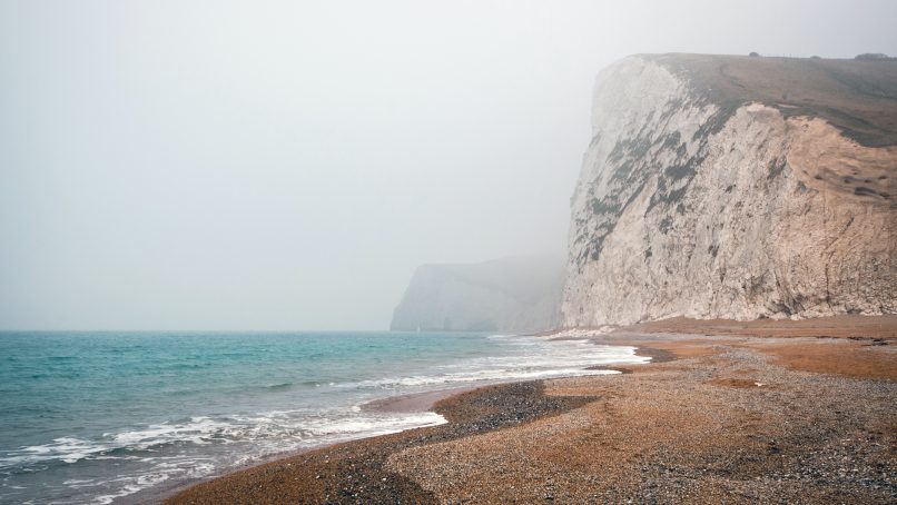 gray rock mountain near body of water at daytime