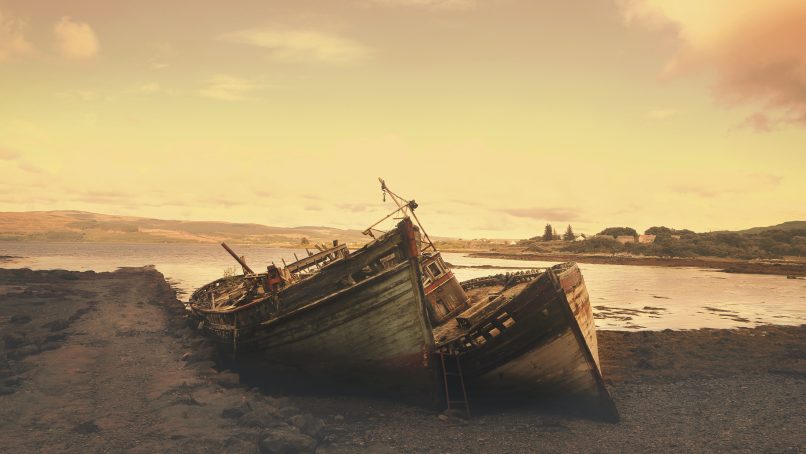 brown wreck boat near seashore during daytime