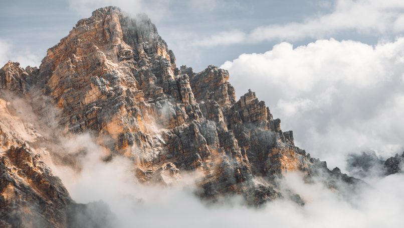 brown and white mountain under white clouds