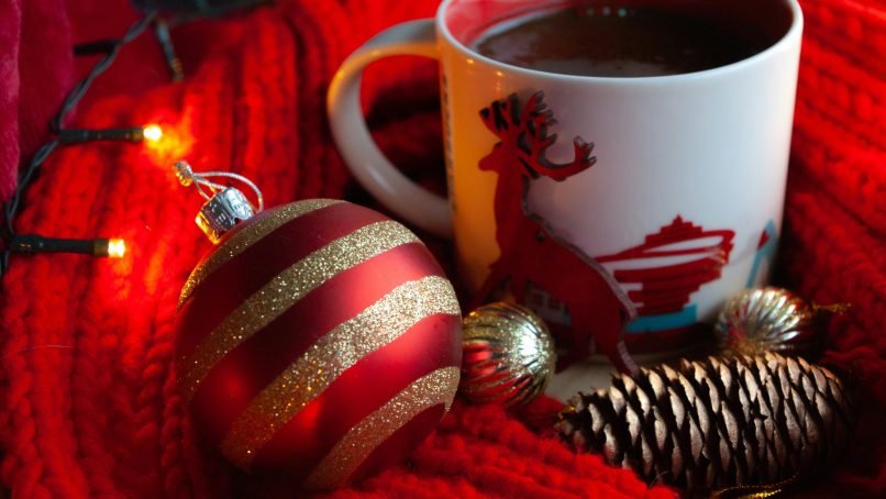 white ceramic mug with coffee beside red and white striped baubles
