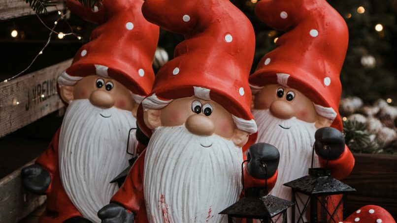 a group of gnomes sitting next to a christmas tree