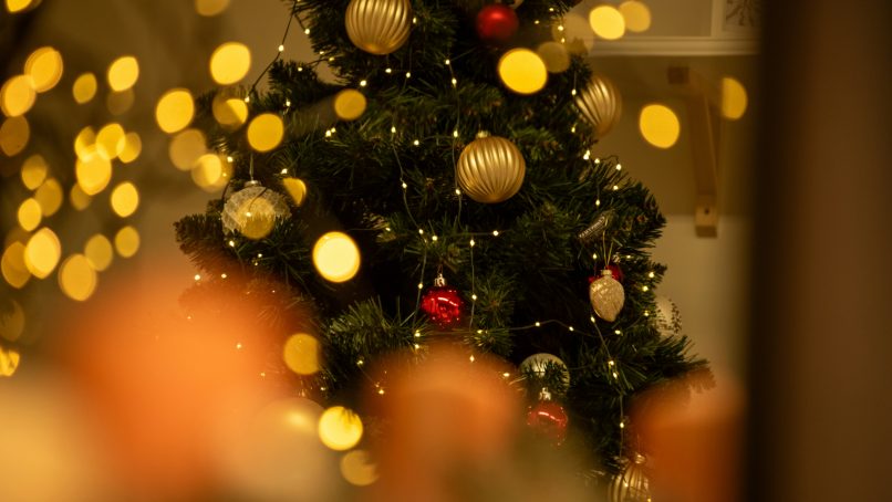 A christmas tree is lit up with gold and red ornaments