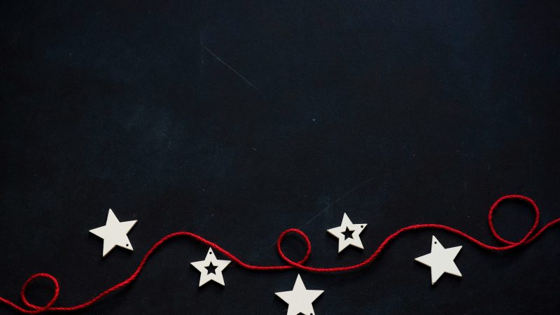 white stars cutout on black surface with red string — Samsung Frame TV art