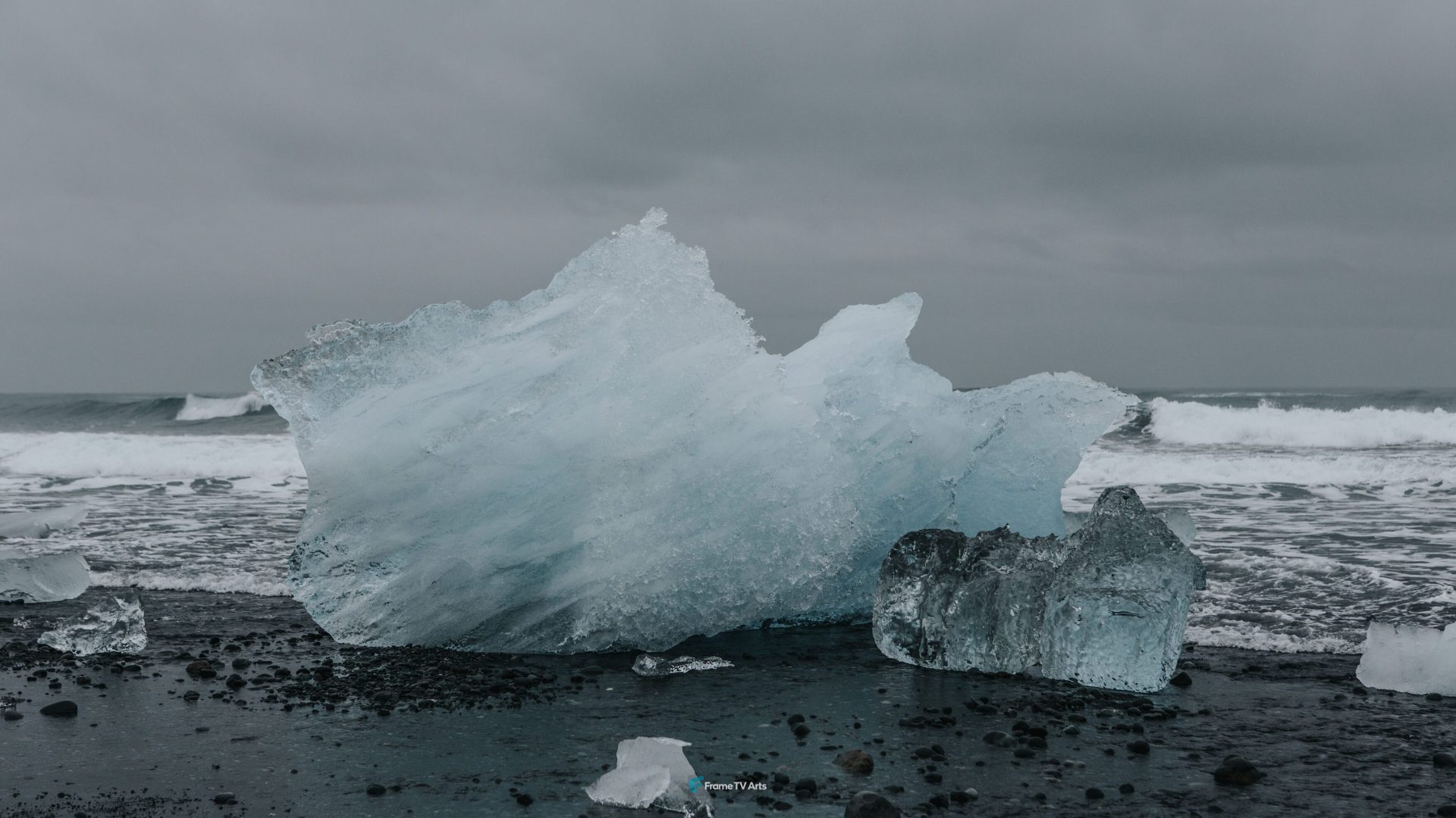 Large iceberg washed ashore on black sand beach with crashing waves. — Samsung Frame TV art