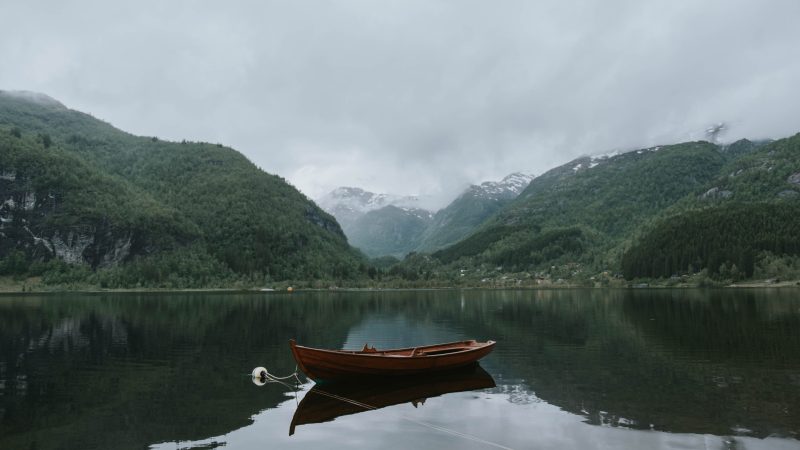 brown boat on body of water near green mountains under white sky at daytime — Samsung Frame TV art