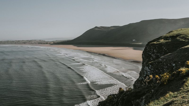 Wide sandy beach with rolling waves and scenic coastal backdrop — Samsung Frame TV art